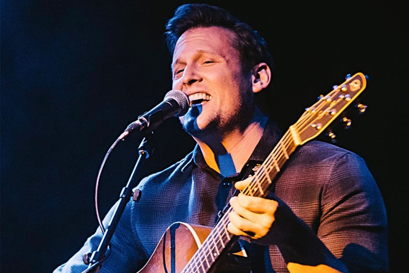 man playing the guitar and singing into a microphone